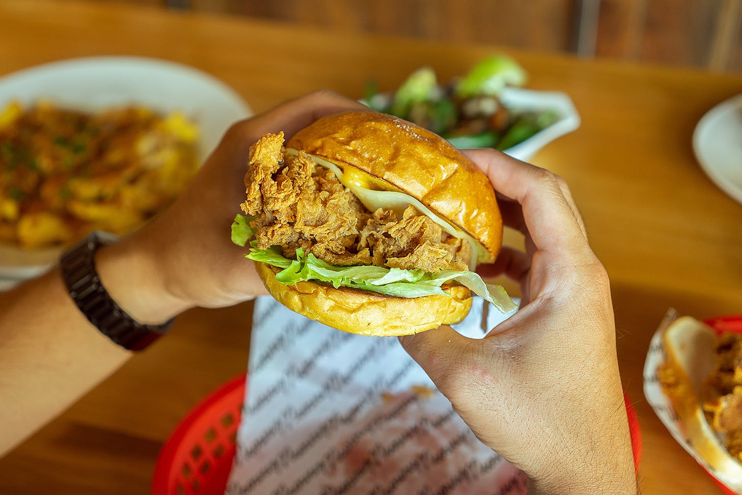 Someone holds a winner winner chicken burger in their hot little hands.